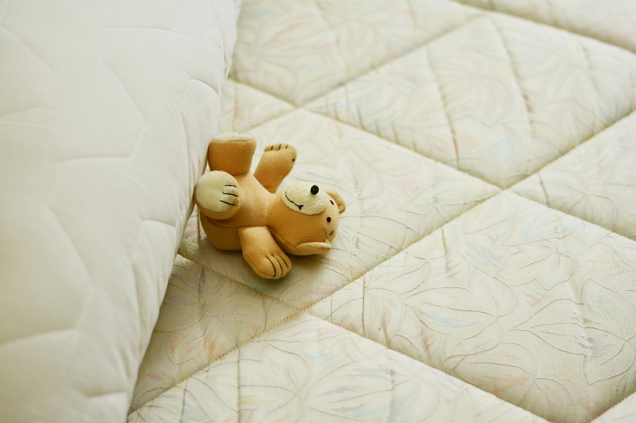 Łóżko dla dziecka. Pluszowy miś, na materacu.